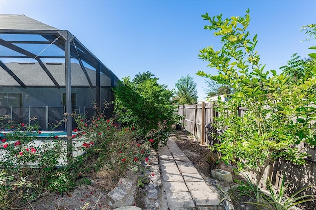 view of yard with glass enclosure and fence