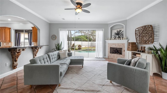 living room featuring ceiling fan, crown molding, and a fireplace