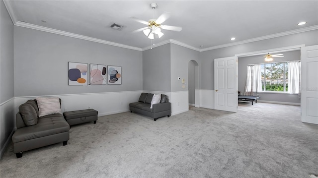 living area with ceiling fan, light colored carpet, and ornamental molding