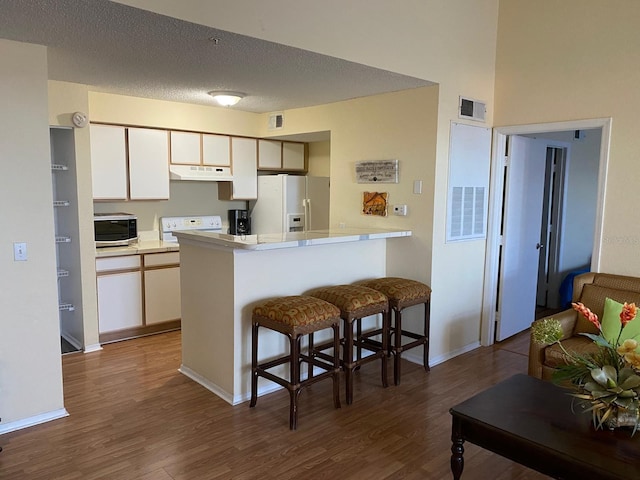 kitchen with kitchen peninsula, dark hardwood / wood-style flooring, white fridge with ice dispenser, and a textured ceiling