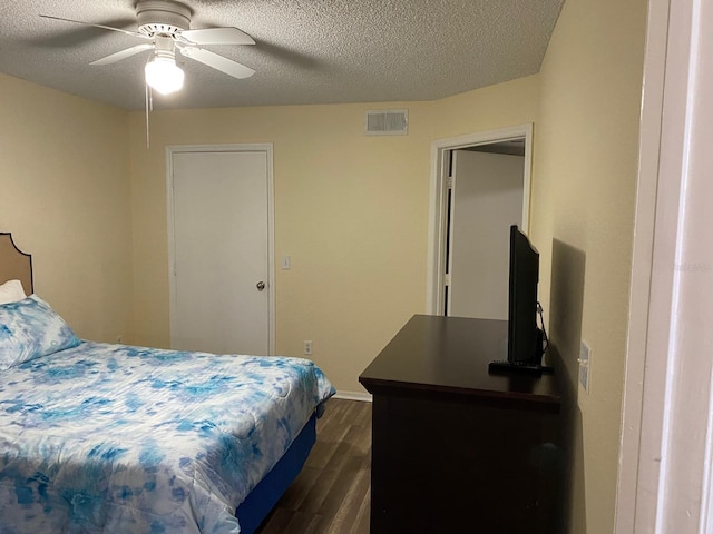 bedroom featuring ceiling fan, dark hardwood / wood-style flooring, and a textured ceiling