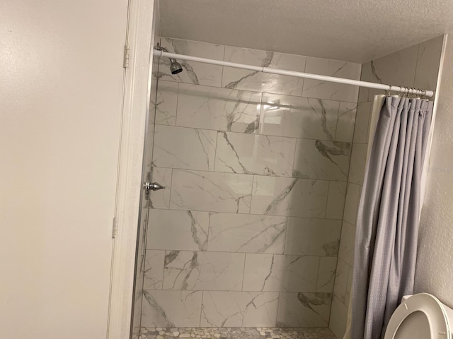 bathroom with toilet, a textured ceiling, and a shower with shower curtain