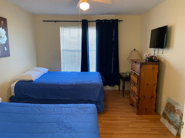 bedroom featuring ceiling fan, light wood-type flooring, and a textured ceiling