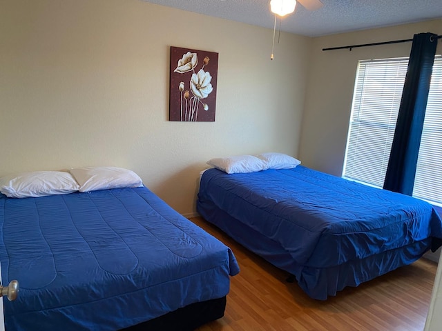 bedroom featuring wood-type flooring, a textured ceiling, and ceiling fan