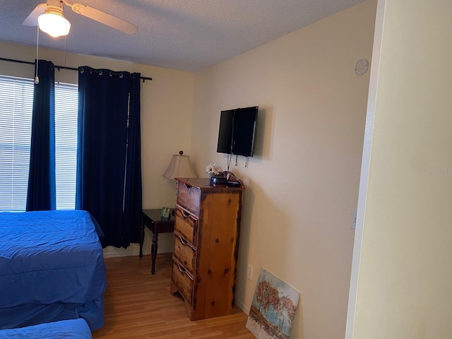 bedroom featuring a textured ceiling, light wood-type flooring, and ceiling fan