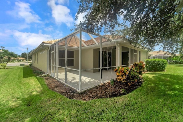 rear view of house with a lanai, a lawn, and a patio