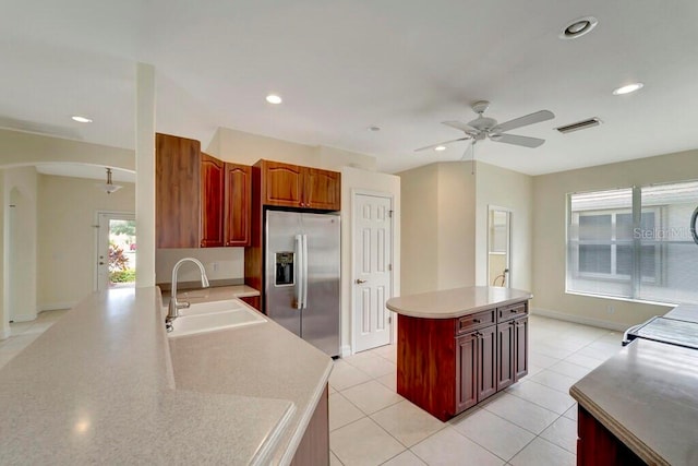 kitchen featuring ceiling fan, a center island, sink, stainless steel refrigerator with ice dispenser, and light tile patterned floors