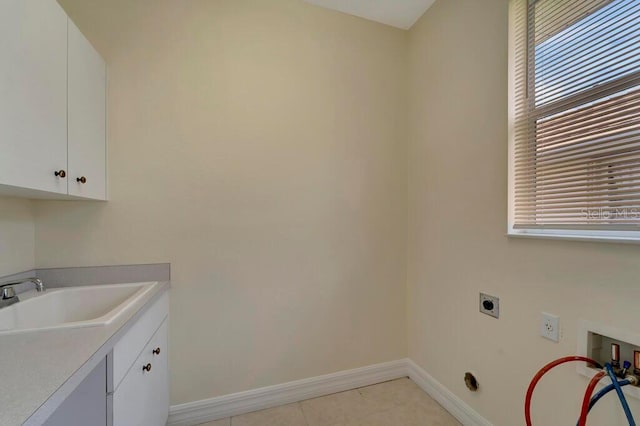 laundry room featuring electric dryer hookup, sink, cabinets, and plenty of natural light