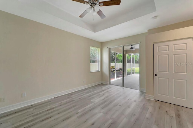 spare room featuring a tray ceiling, light hardwood / wood-style flooring, and ceiling fan