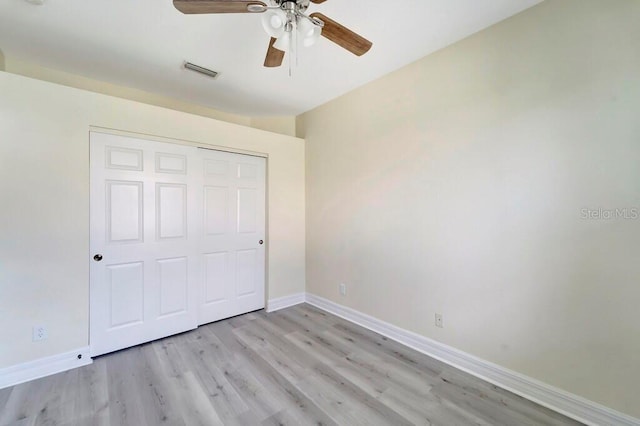 unfurnished bedroom with ceiling fan, light wood-type flooring, and a closet