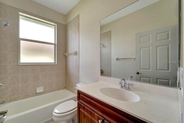 full bathroom with tiled shower / bath, vanity, and toilet