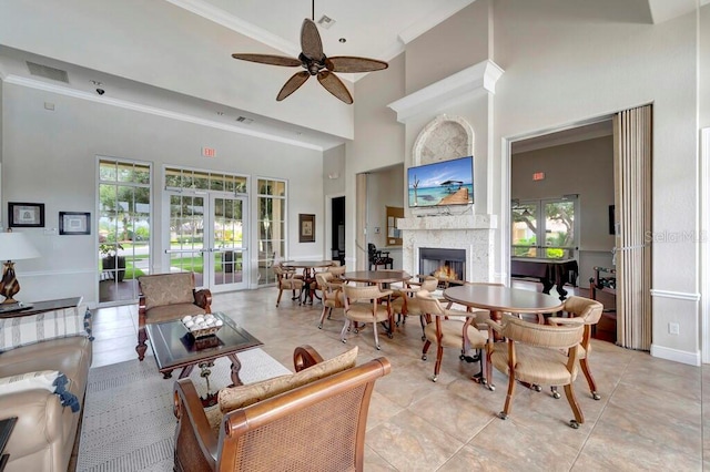 tiled living room featuring ceiling fan, a towering ceiling, crown molding, and french doors