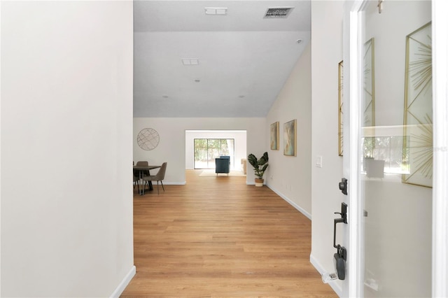 corridor with light hardwood / wood-style floors and lofted ceiling