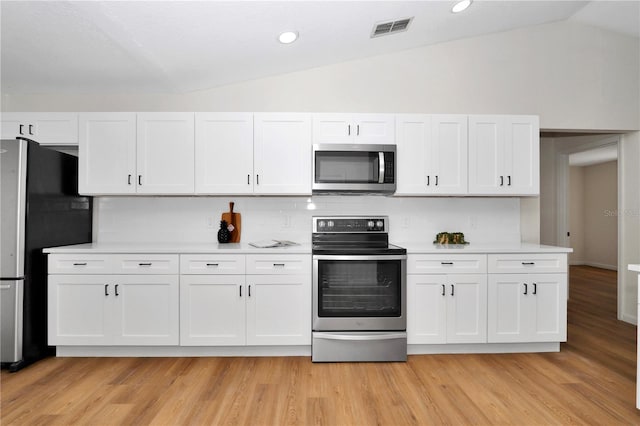 kitchen featuring white cabinets, appliances with stainless steel finishes, light wood-type flooring, and lofted ceiling