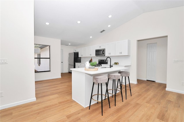 kitchen with white cabinetry, sink, light hardwood / wood-style floors, a breakfast bar, and appliances with stainless steel finishes