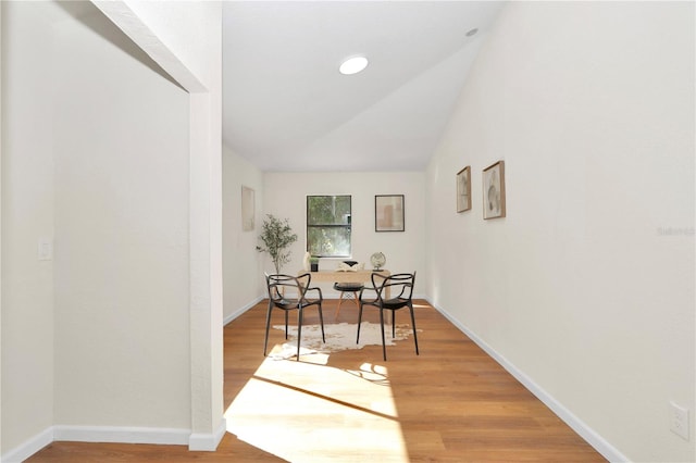 corridor featuring wood-type flooring and vaulted ceiling