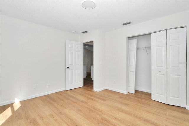 unfurnished bedroom with a textured ceiling, light hardwood / wood-style flooring, and a closet