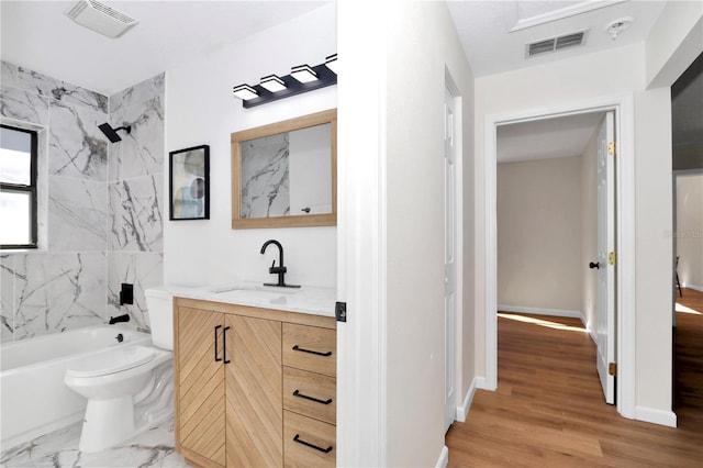 full bathroom featuring vanity, toilet, wood-type flooring, and tiled shower / bath