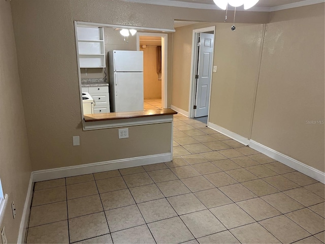 kitchen with ceiling fan, white fridge, light tile patterned floors, and crown molding