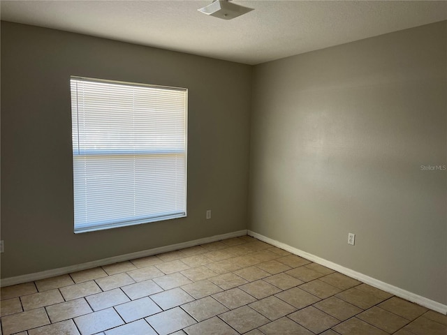 spare room with a textured ceiling and light tile patterned flooring