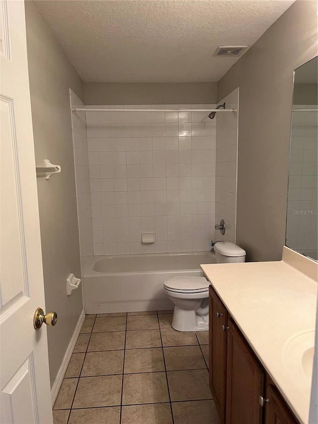 full bathroom featuring vanity, tiled shower / bath, tile patterned flooring, toilet, and a textured ceiling