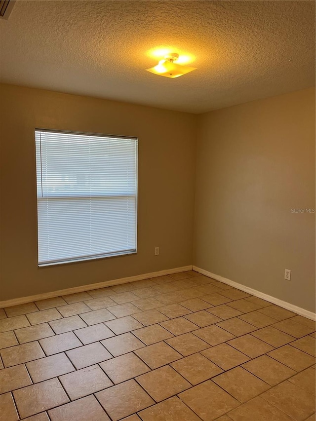 tiled empty room with a textured ceiling