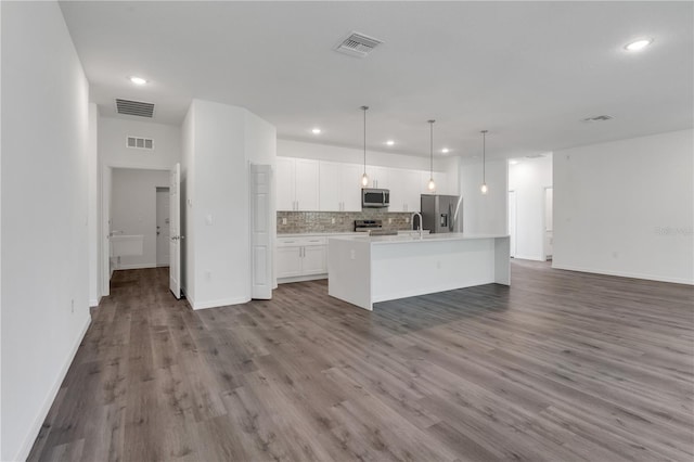 kitchen with wood-type flooring, stainless steel appliances, white cabinetry, and pendant lighting