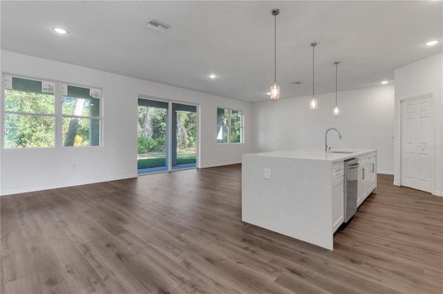 kitchen featuring dishwasher, hanging light fixtures, an island with sink, dark hardwood / wood-style flooring, and white cabinetry