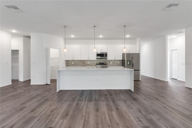 kitchen featuring pendant lighting, a kitchen island with sink, dark hardwood / wood-style floors, white cabinetry, and stainless steel appliances