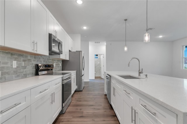 kitchen with stainless steel appliances, dark wood-type flooring, sink, white cabinets, and hanging light fixtures