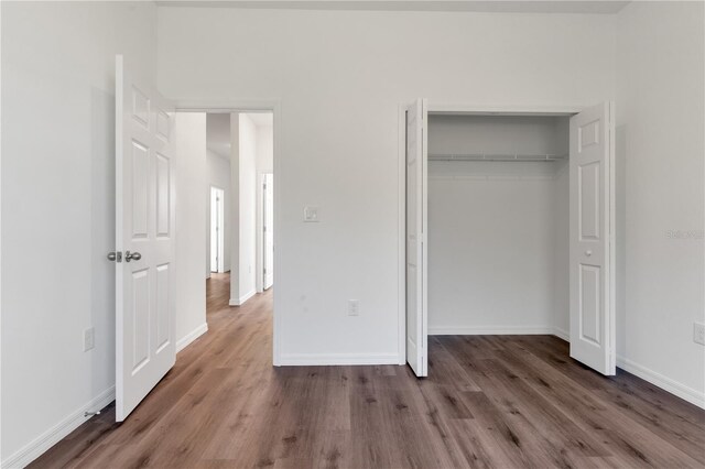 unfurnished bedroom with dark hardwood / wood-style flooring and a closet