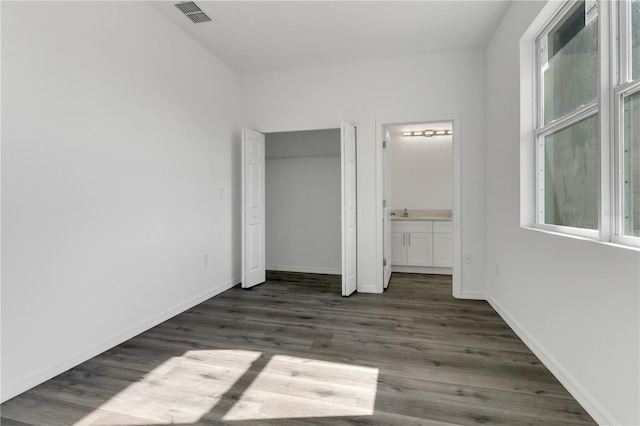 unfurnished bedroom featuring dark hardwood / wood-style floors and ensuite bathroom