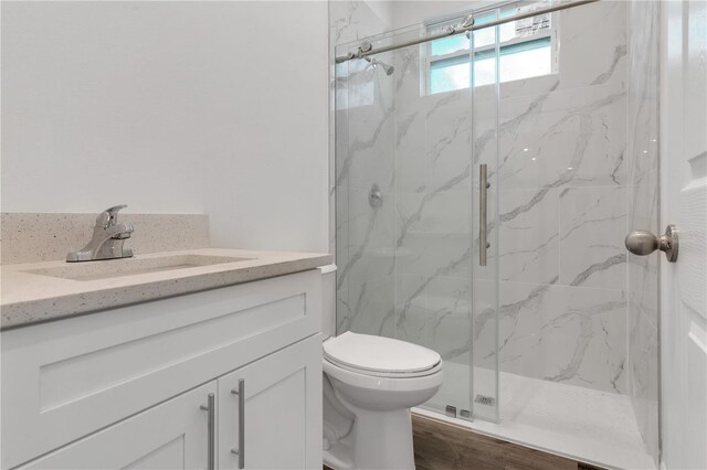 bathroom featuring walk in shower, vanity, wood-type flooring, and toilet