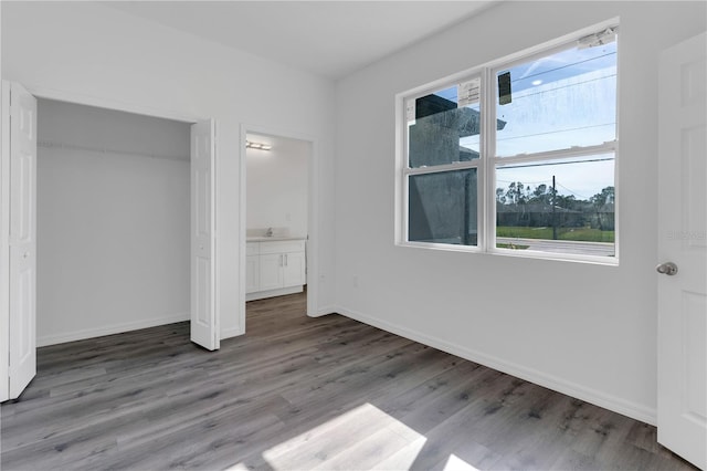 unfurnished bedroom featuring multiple windows, a closet, and hardwood / wood-style floors