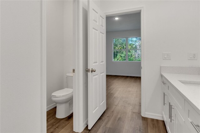 bathroom with hardwood / wood-style floors, vanity, and toilet