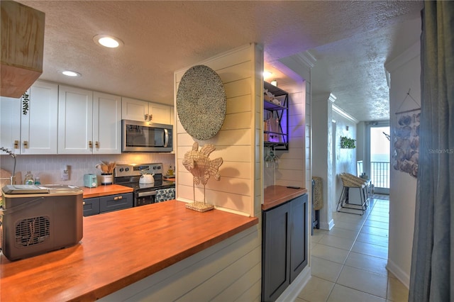 kitchen featuring appliances with stainless steel finishes, a textured ceiling, butcher block countertops, and white cabinetry