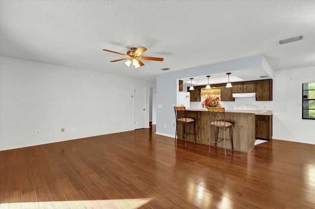 unfurnished living room featuring a textured ceiling, ceiling fan, and dark wood-type flooring