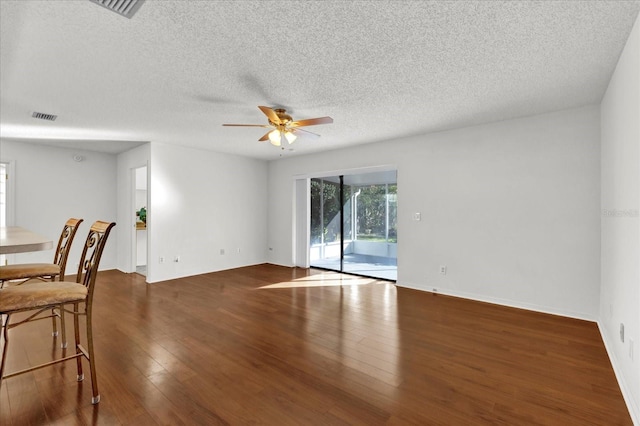 unfurnished room featuring a textured ceiling, ceiling fan, and dark wood-type flooring