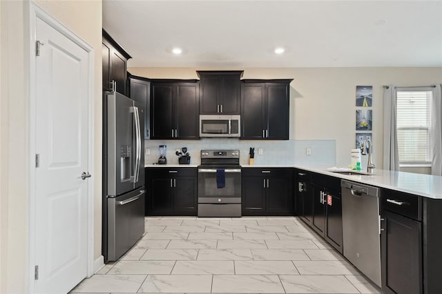 kitchen with tasteful backsplash, kitchen peninsula, sink, and appliances with stainless steel finishes