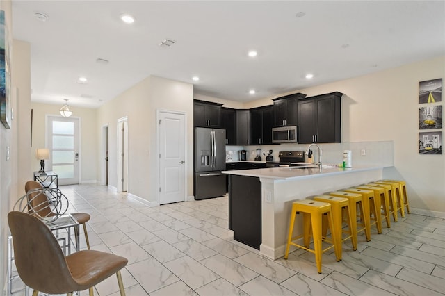 kitchen with kitchen peninsula, a kitchen breakfast bar, backsplash, stainless steel appliances, and sink