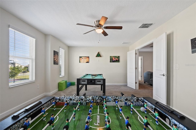 recreation room featuring ceiling fan, carpet, and a textured ceiling