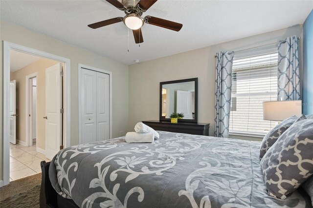 bedroom with ceiling fan, light tile patterned floors, and a closet