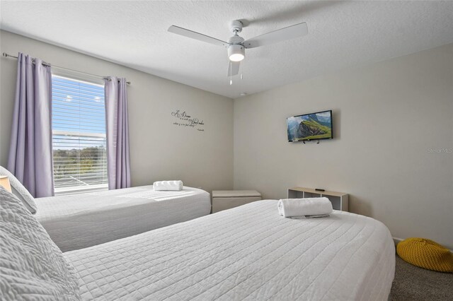 carpeted bedroom featuring ceiling fan and a textured ceiling