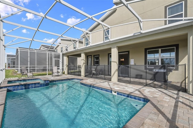 view of pool featuring glass enclosure, an in ground hot tub, and a patio