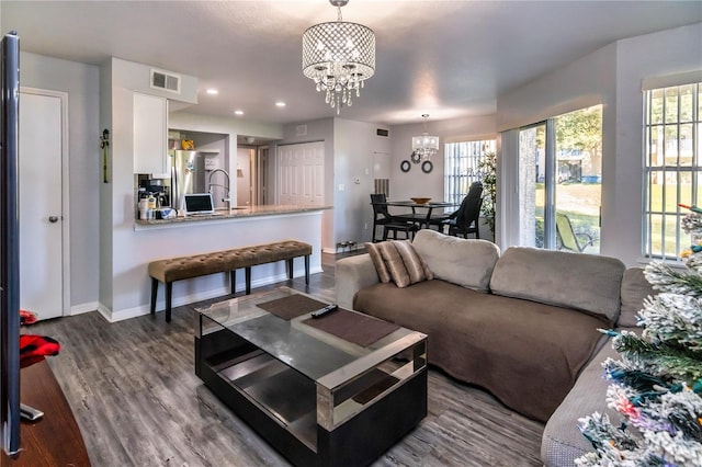 living room with a wealth of natural light, dark wood-type flooring, and a notable chandelier