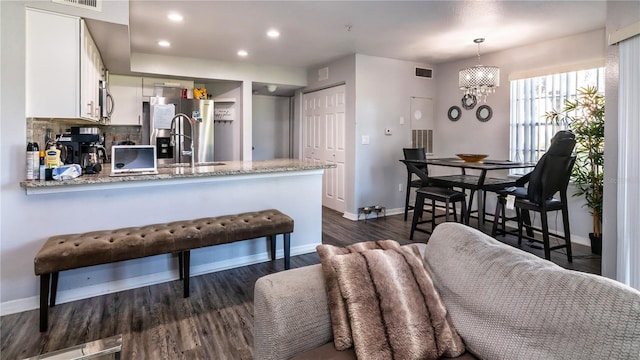 kitchen featuring white cabinetry, kitchen peninsula, stainless steel appliances, and dark wood-type flooring