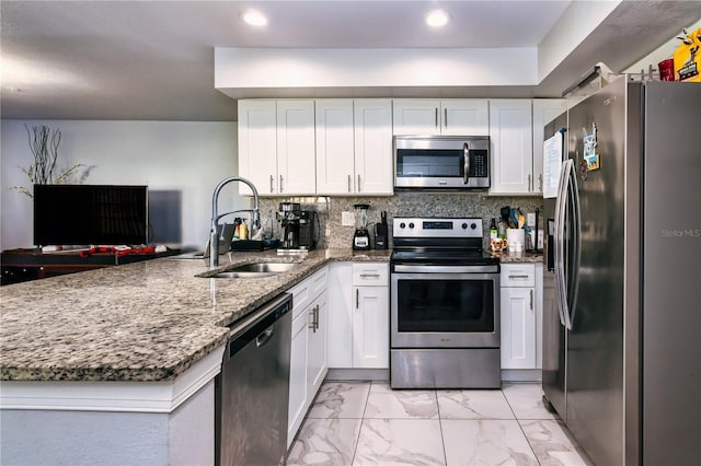 kitchen with kitchen peninsula, appliances with stainless steel finishes, white cabinetry, and sink