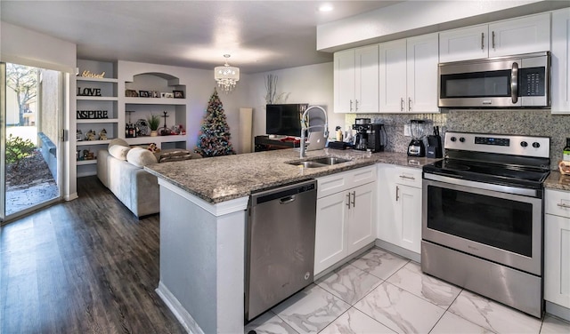 kitchen featuring kitchen peninsula, stainless steel appliances, white cabinetry, and sink