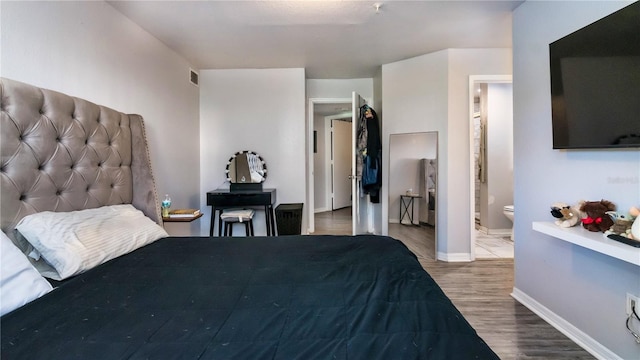 bedroom featuring ensuite bath and hardwood / wood-style flooring