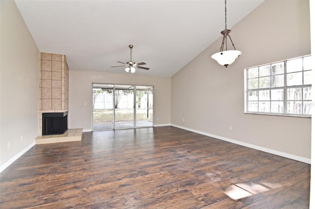 unfurnished living room with a tile fireplace, dark hardwood / wood-style floors, vaulted ceiling, and ceiling fan